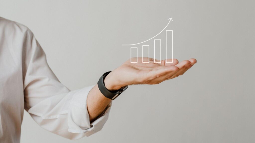 An increasing bar graph over a businessman’s hand